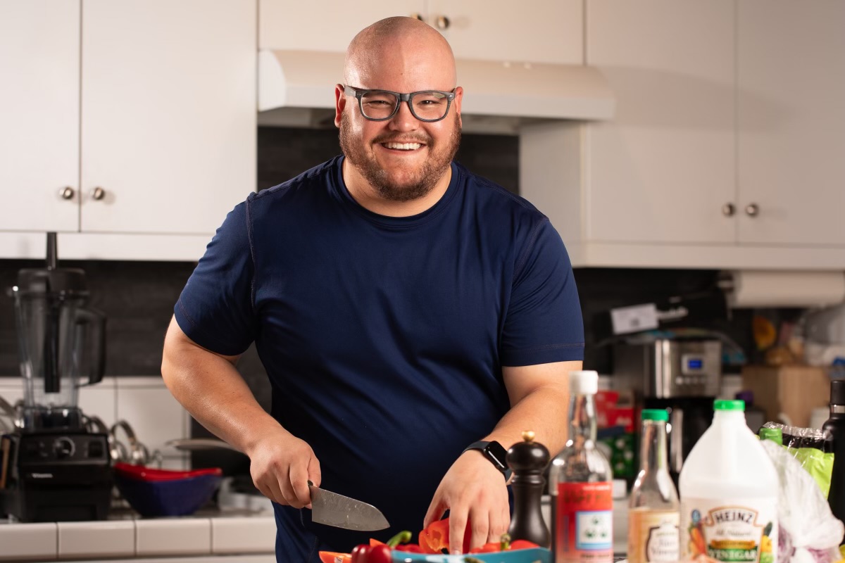 Ethan smiling as he prepares food in his kitchen